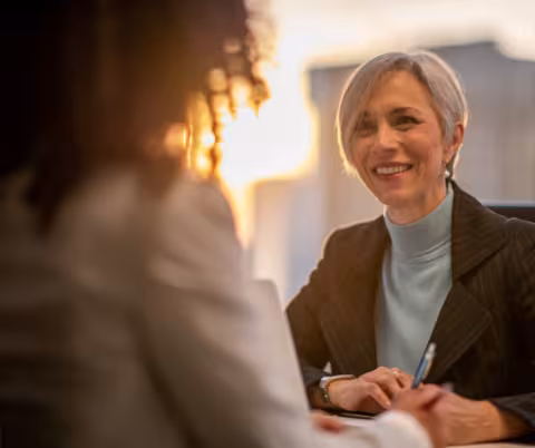 Two women facing one another, one smiling at the other